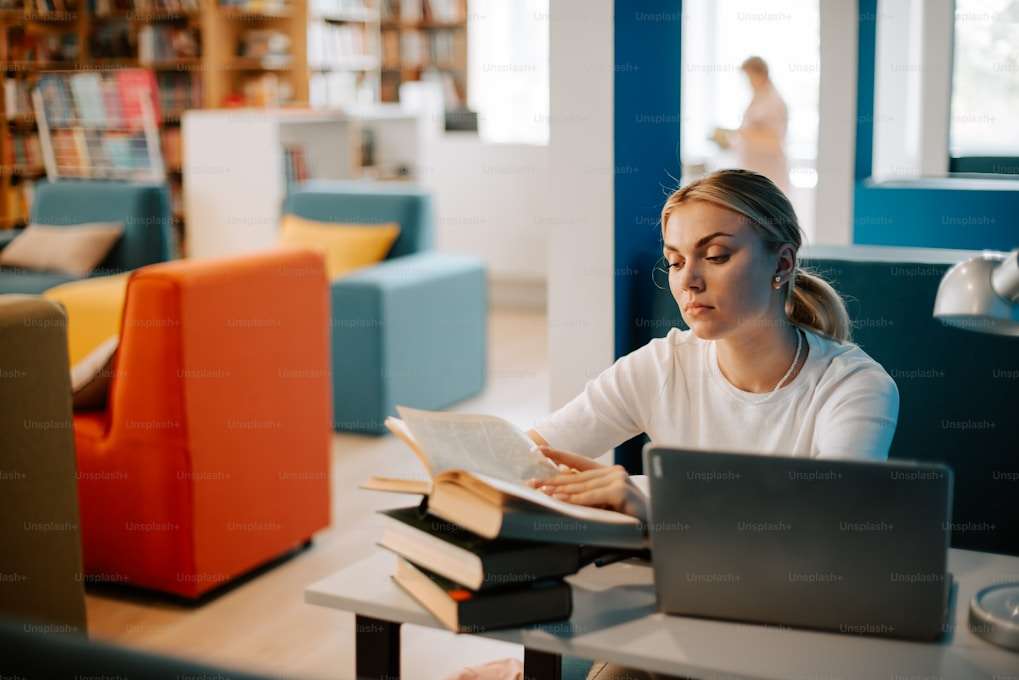Une femme devant un ordinateur et une pile de livres