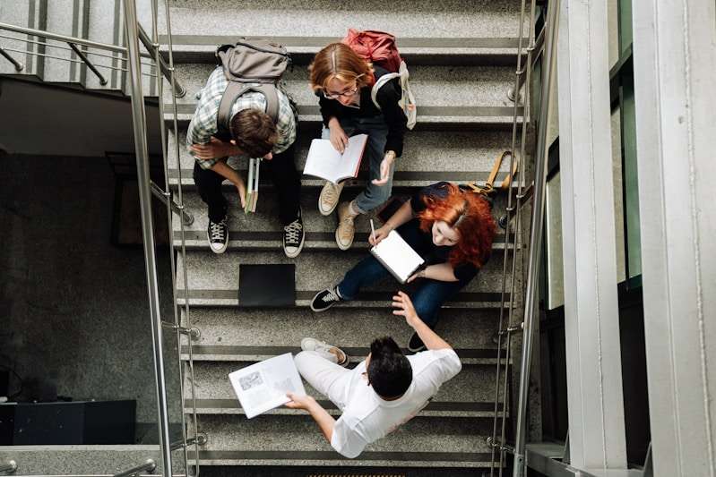 4 étudiants dans un escalier avec des livres ouverts dans leur main